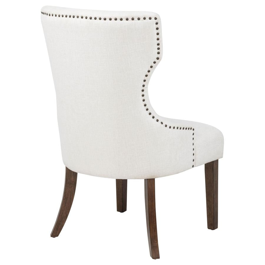Modern ivory upholstered dining chair with nailhead trim and dark wood legs, ideal for dining room