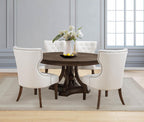 Round dark wood dining table with cream upholstered chairs in elegant dining room