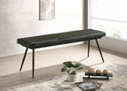 Modern black leather upholstered dining bench with tapered metal legs positioned beside a bright window.
