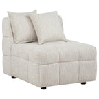 Cream upholstered armless chair with channeled quilted details, two throw pillows, and black legs.