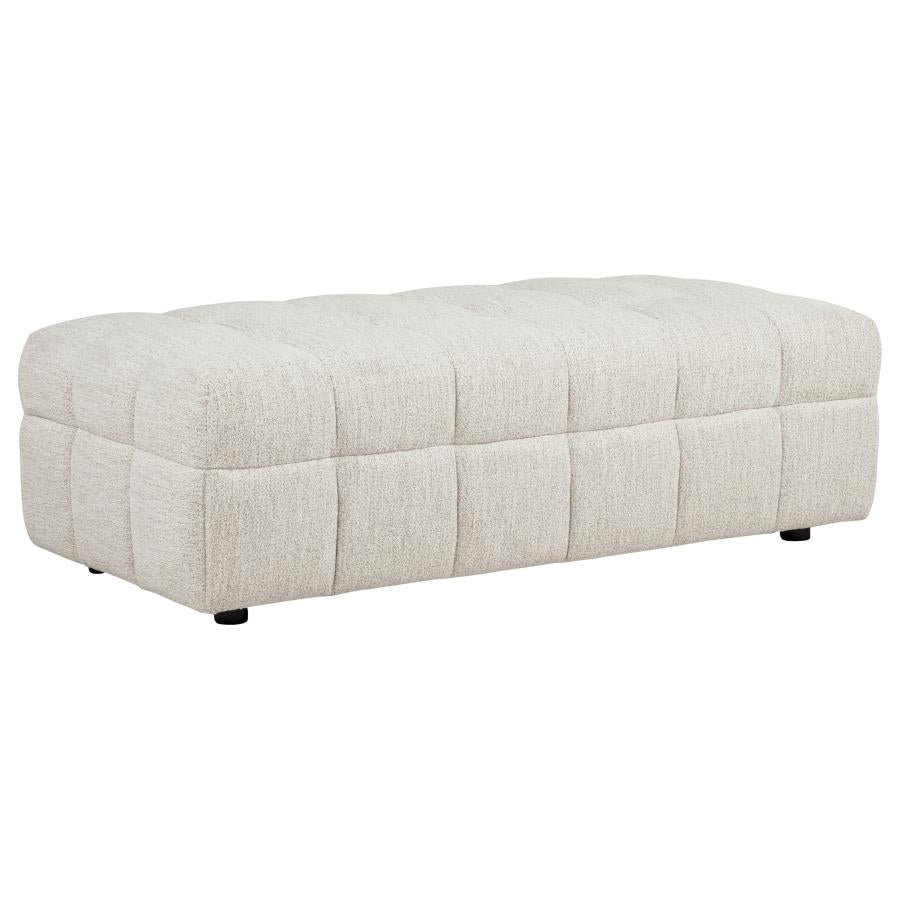 Cream quilted upholstered ottoman with channel-tufted design and black legs on white background.
