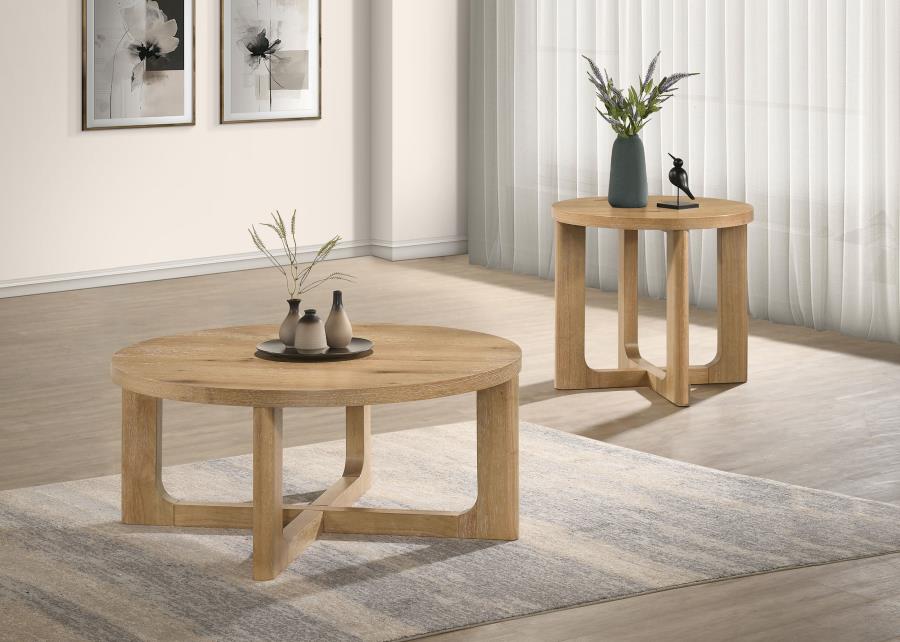 Two light oak round coffee tables with sculptural wooden bases arranged on a gray area rug in a minimalist living room.